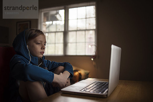 Junge benutzt Laptop-Computer auf dem Tisch  während er zu Hause sitzt