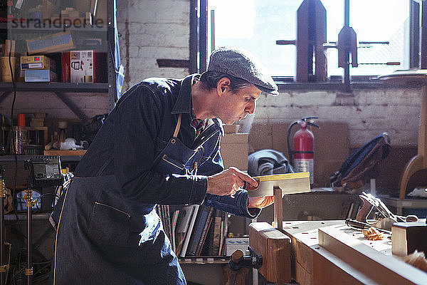 Zimmermann schneidet Holz mit der Handsäge in der Werkstatt