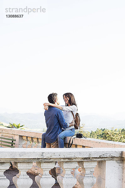 Romantisches Paar umarmt sich auf der Terrasse vor klarem Himmel