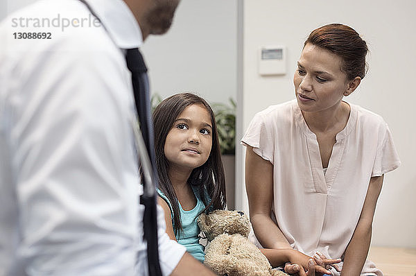 Mutter sieht Mädchen an und hört dem Arzt zu  während sie im Krankenhaus sitzt