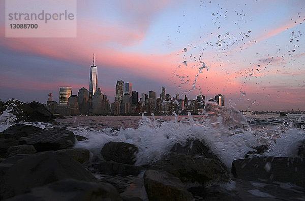 Fließender Fluss gegen das Stadtbild in New York City in der Abenddämmerung