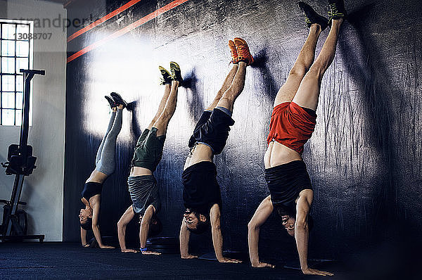 Entschlossene Athleten machen Handstand im Fitnessstudio