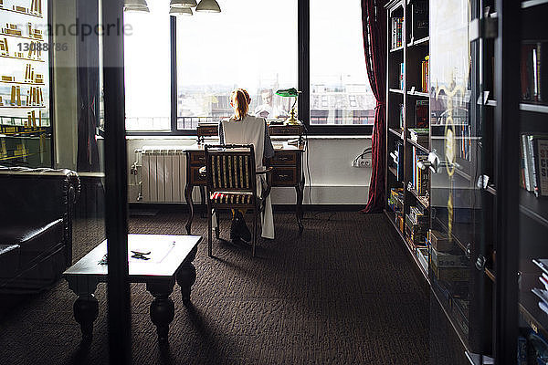 Rückansicht einer Geschäftsfrau  die am Schreibtisch im Kreativbüro arbeitet
