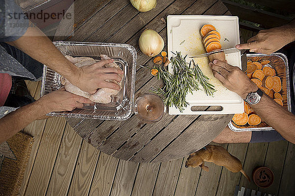 Beschnittenes Bild von schwulen Männern  die am Holztisch Essen machen