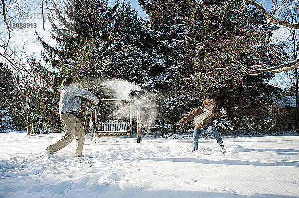 Glückliche Brüder spielen im Hinterhof mit Schnee