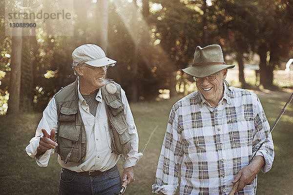 Glückliche ältere Männer halten beim Waldspaziergang Angelruten