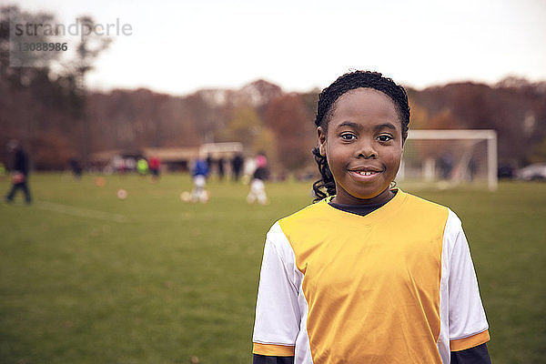 Porträt eines lächelnden Fußballspielers auf dem Spielfeld stehend