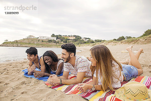 Glückliche multiethnische Freunde entspannen sich an der Küste am Strand