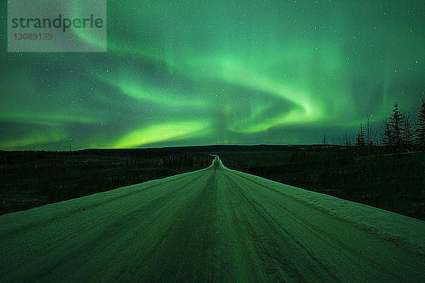 Landschaftliche Ansicht des Polarlichts über einer schneebedeckten Straße