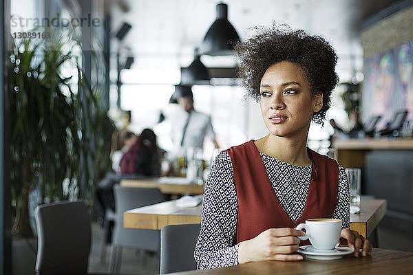 Nachdenkliche Frau hält Kaffeetasse im Café