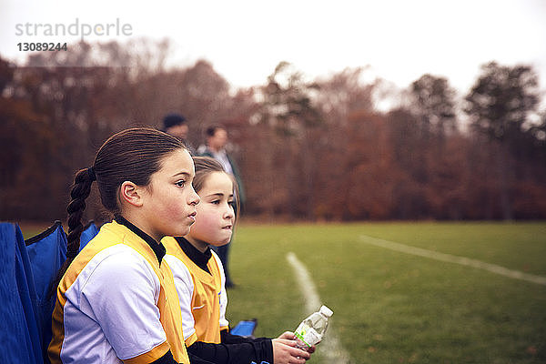 Freunde in Sportuniform ruhen auf Stuhl am Fussballplatz