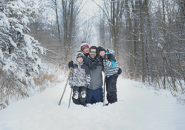 Porträt eines Vaters mit Söhnen auf verschneitem Feld vor kahlen Bäumen
