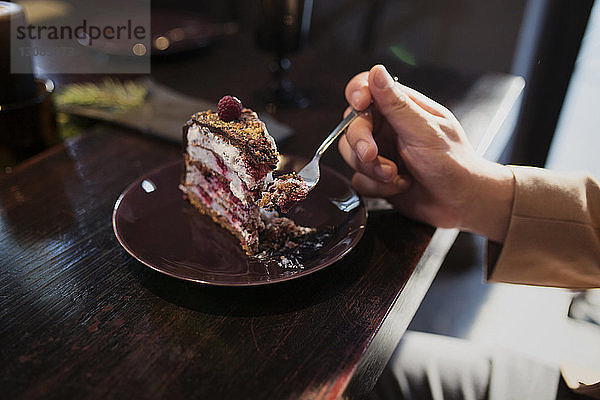 Ausgeschnittenes Bild eines Mannes  der bei Tisch ein Kuchenstück isst