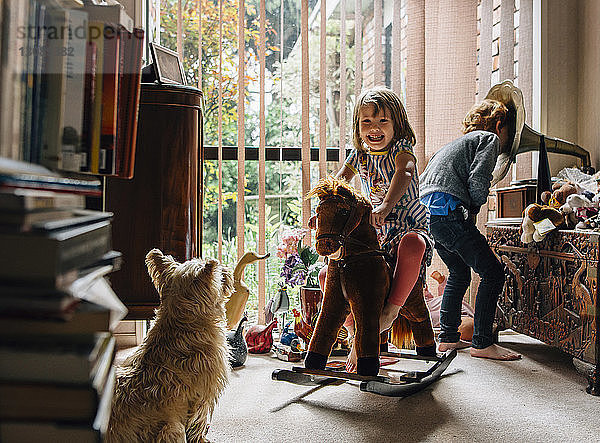 Glückliche Geschwister spielen zu Hause mit Hund im Vordergrund