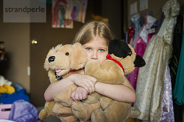 Mädchen hält zu Hause Plüschtiere im Schlafzimmer