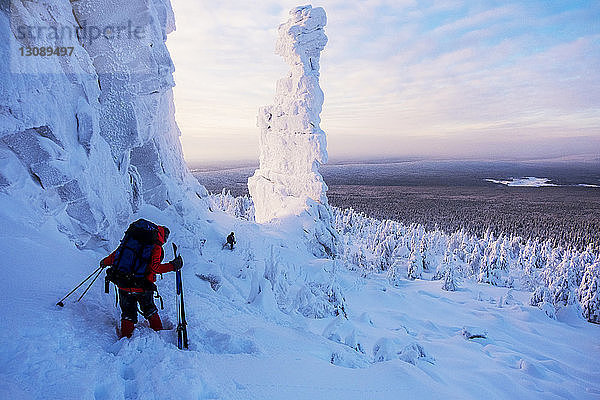 Freunde wandern in schneebedeckter Landschaft gegen wolkigen Himmel