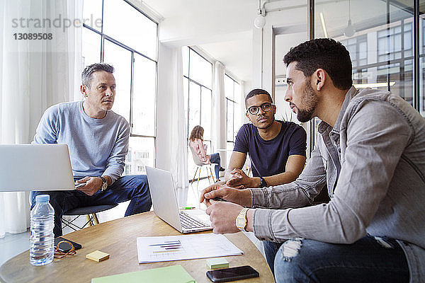 Männliche Kollegen diskutieren bei einer Besprechung im Büro