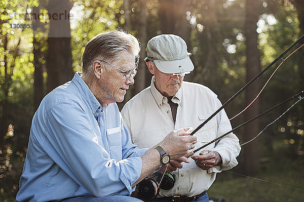 Ältere männliche Freunde untersuchen Angelruten im Wald