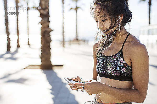 Sportliche Frau hört im Sommer auf Wanderwegen Musik über Smartphone