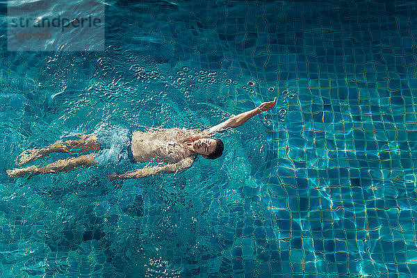 Hochwinkelansicht eines Mannes ohne Hemd  der im Schwimmbad des Ferienorts schwimmt
