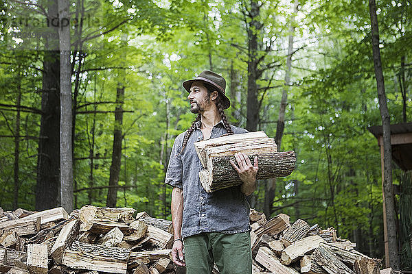 Tiefwinkelansicht eines Mannes mit Brennholz  der im Wald wegschaut