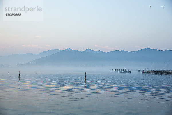 Landschaftliche Ansicht des Sees durch die Silhouette der Berge gegen den Himmel bei Sonnenuntergang