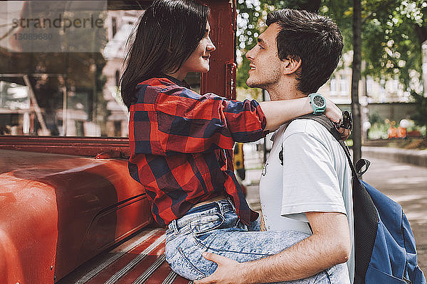 Seitenansicht eines jungen Paares  das sich in der Stadt mit einem Oldtimer-Bus von Angesicht zu Angesicht gegenübersteht