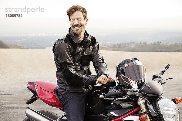 Fröhlicher Motorradfahrer sitzt auf einem Motorrad auf dem Land