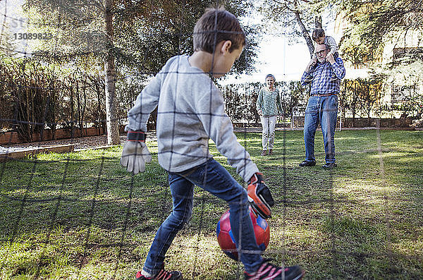 Junge spielt mit Familie auf dem Hof Fussball