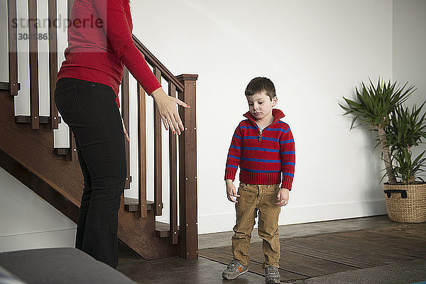 Verärgerter Junge steht mit der Mutter zu Hause