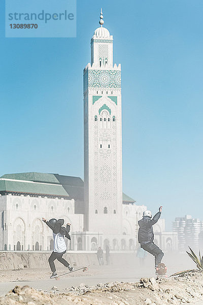 Skateboarding in voller Länge der Freunde gegen die Moschee Hassan II