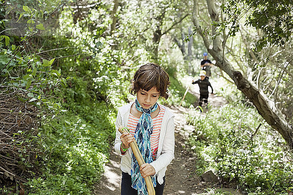 Mädchen hält Stock beim Gehen auf Waldweg
