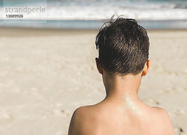 Rückansicht eines Jungen ohne Hemd am Strand im Sommer