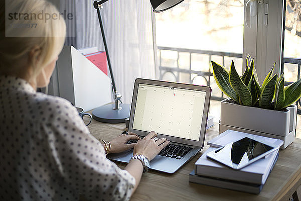 Rückansicht einer Frau am Laptop im Heimbüro