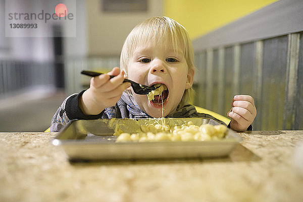 Porträt eines am Tisch sitzenden Jungen beim Essen