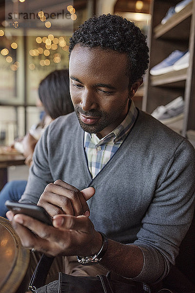Junger Mann verschickt Textnachrichten  während er im Café sitzt