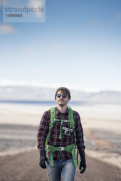 Wanderer mit Kamera erkundet Wüste gegen Himmel