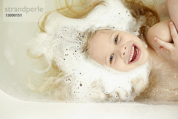 Draufsicht eines fröhlichen Mädchens beim Baden in der Badewanne