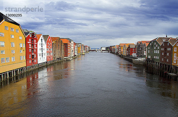 Nidelva-Fluss inmitten von Häusern gegen bewölkten Himmel