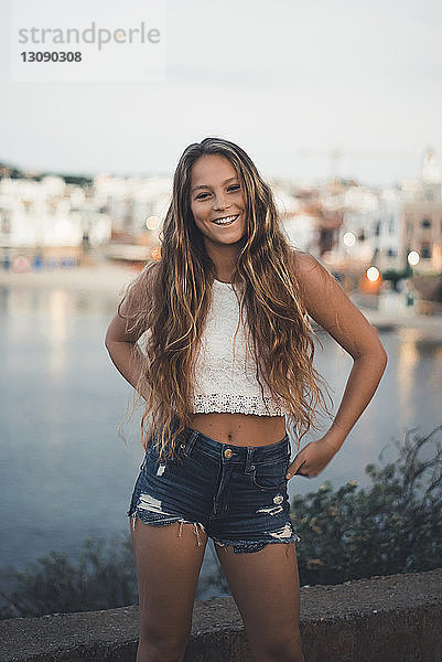 Porträt einer Teenagerin  die bei Sonnenuntergang in der Stadt am Meer steht