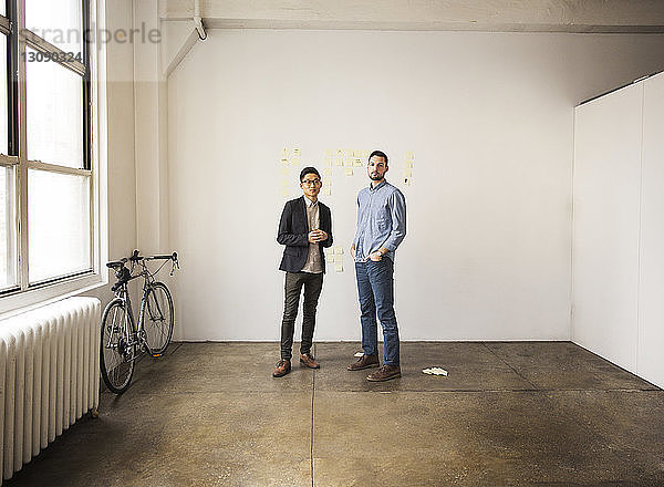 Geschäftsleute stehen im Kreativbüro an weißer Wand