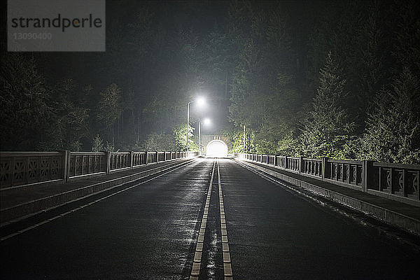 Ansicht eines Straßentunnels bei Bäumen während der Nacht