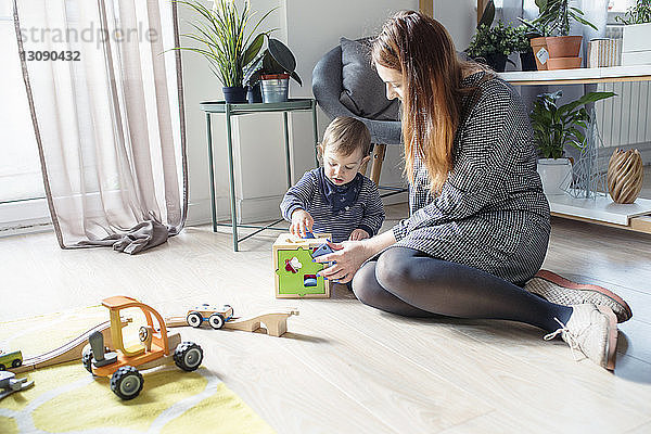 Mutter und Sohn spielen mit Spielzeug  während sie zu Hause auf dem Boden sitzen