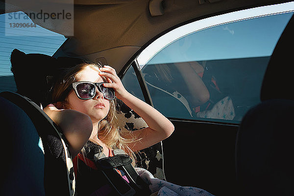 Mädchen mit Sonnenbrille sitzt im Auto