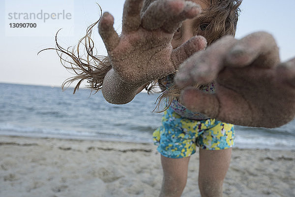 Porträt eines Mädchens mit unordentlichen Händen  das am Strand vor klarem Himmel steht