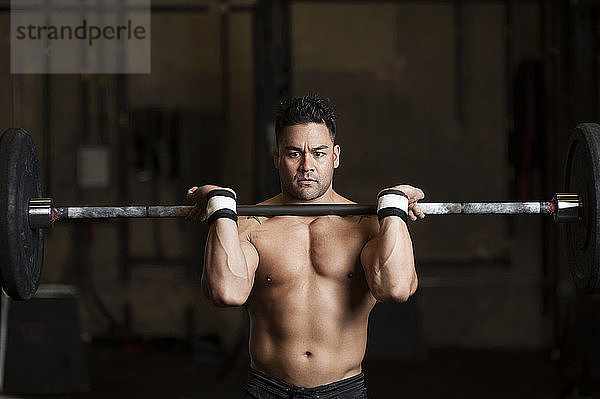 Schwerer Mann hebt Hanteln im Fitnessstudio