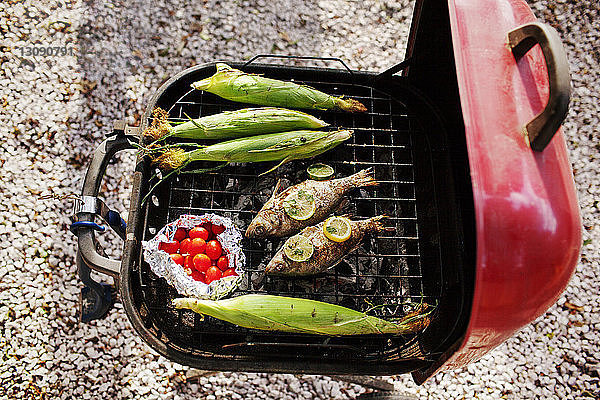 Draufsicht auf Fisch und Mais mit Kirschtomaten auf dem Barbecue-Grill