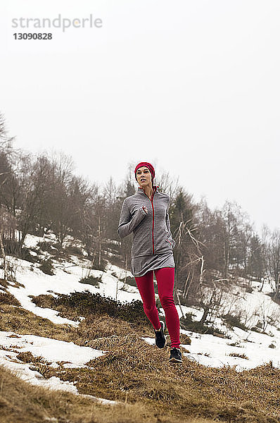 Entschlossene Sportlerin  die im Winter am Berg läuft