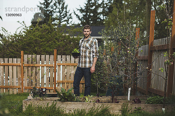 Porträt eines Mannes mit Pflanze im Hinterhof