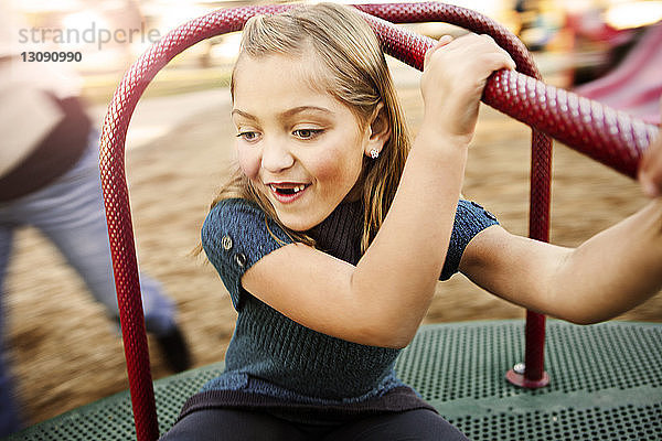 Glückliches Mädchen spielt auf Karussell im Park